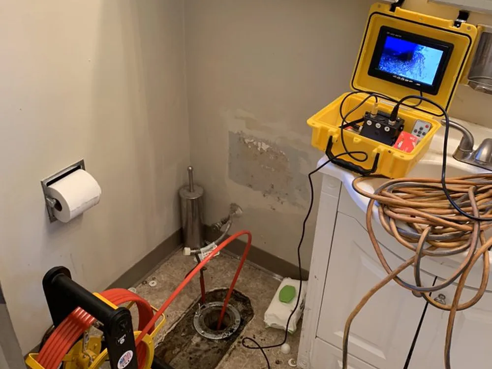 Sewer camera monitor and cable reel set up at an opened floor cleanout