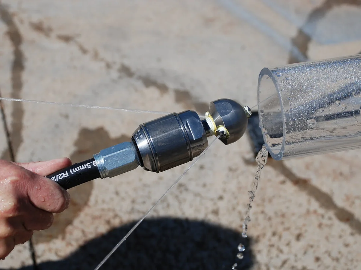 Hydro jetting nozzle and hose running into an outdoor drain cleanout