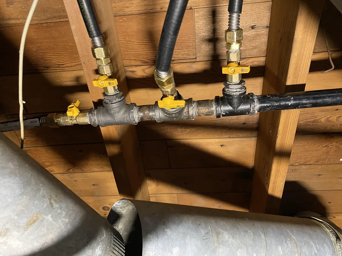 Black iron gas piping with shutoff valves branching across a basement ceiling