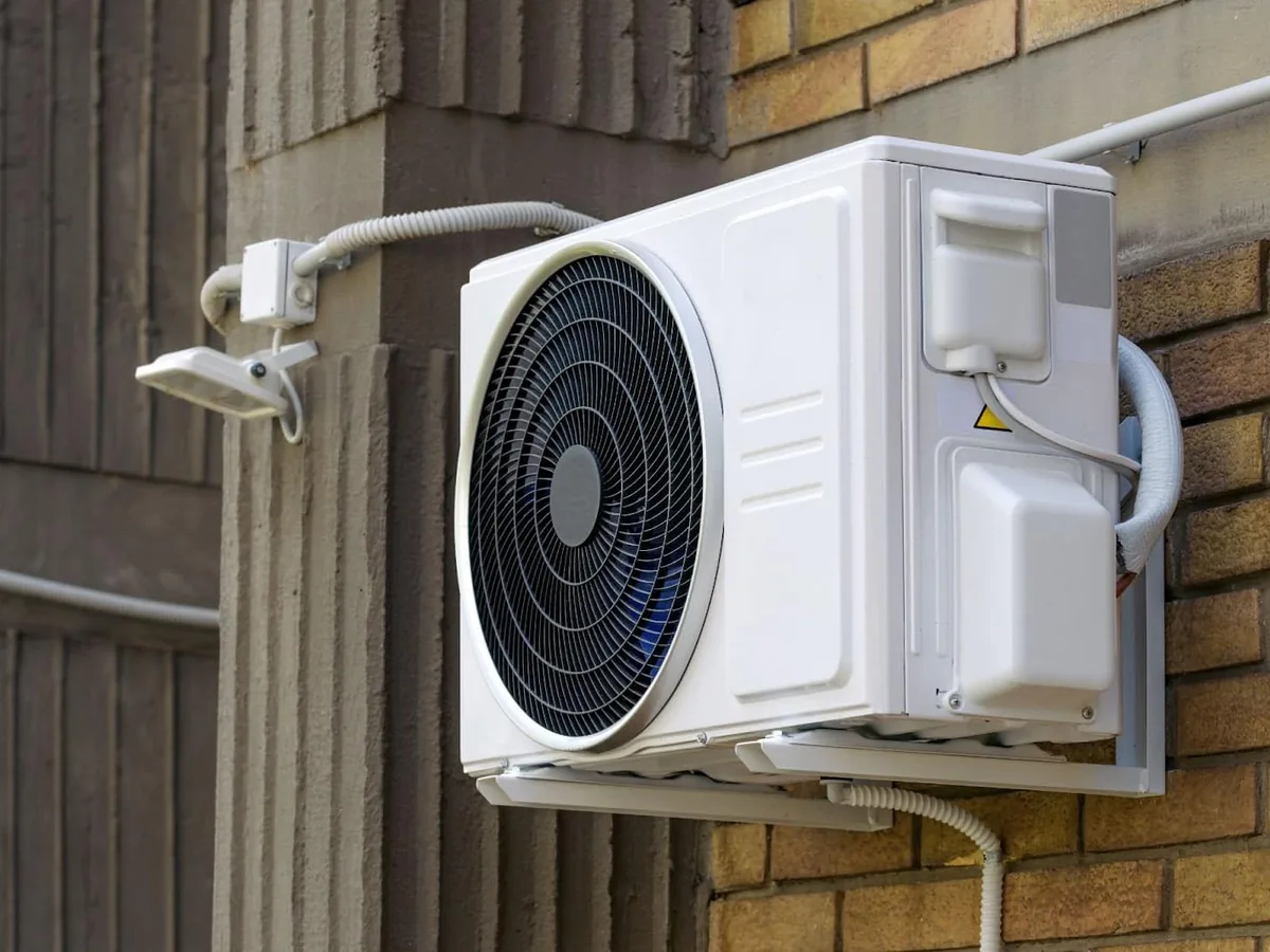 Mini split outdoor condenser bracketed to a masonry exterior wall