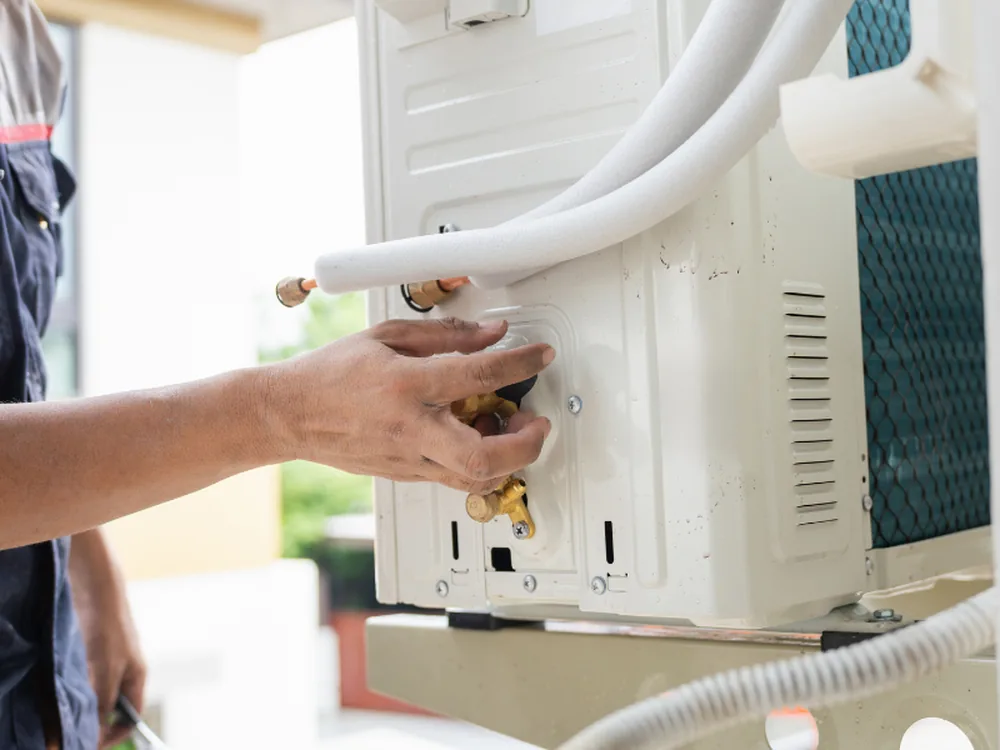 Hands connecting the line set at a mini split outdoor unit