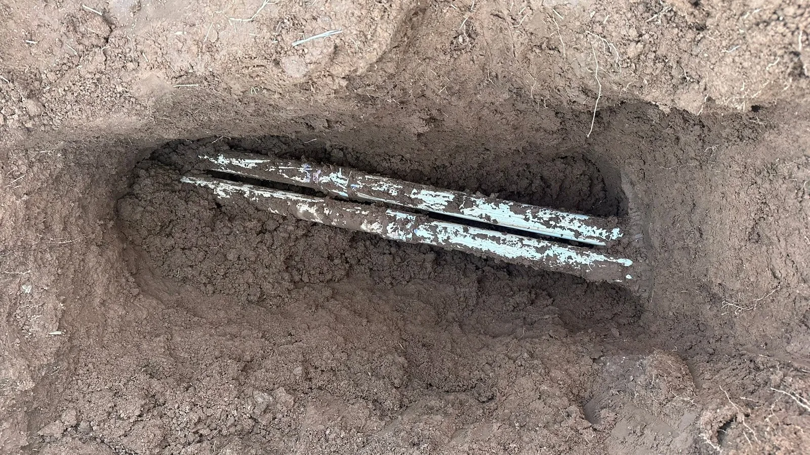 Old corroded water line exposed in a hand-dug trench in New Mexico