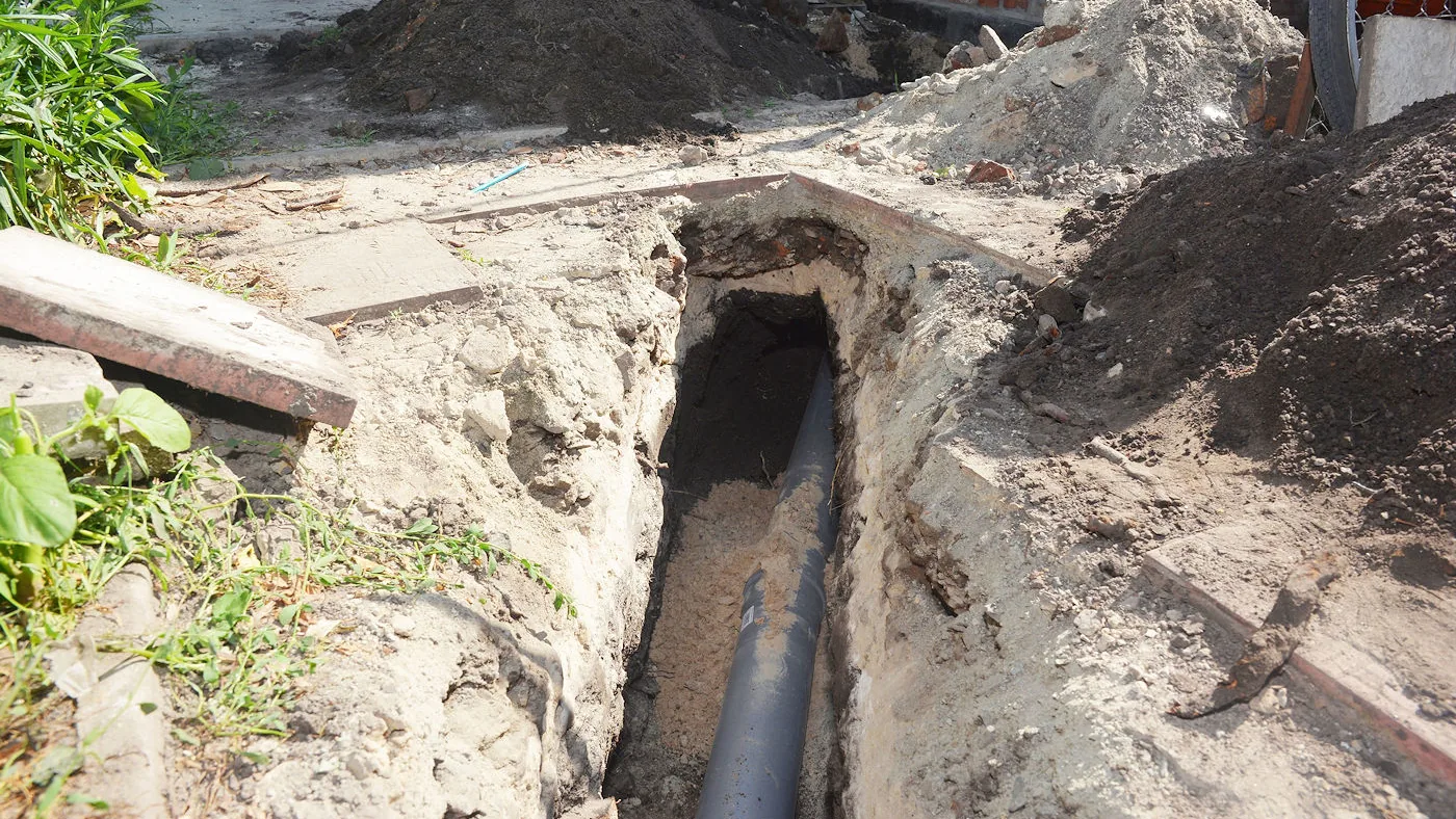 New pipe bedded in the bottom of a deep pipe trench dug beside a building