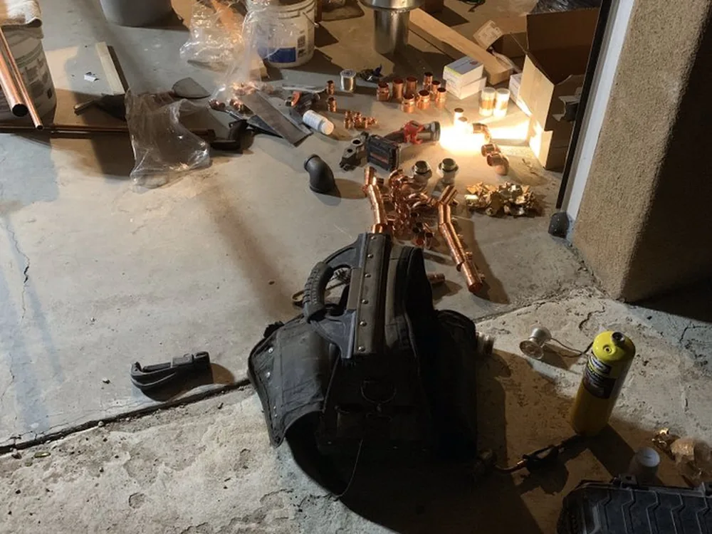 Copper fittings and a torch laid out at an opened floor drain