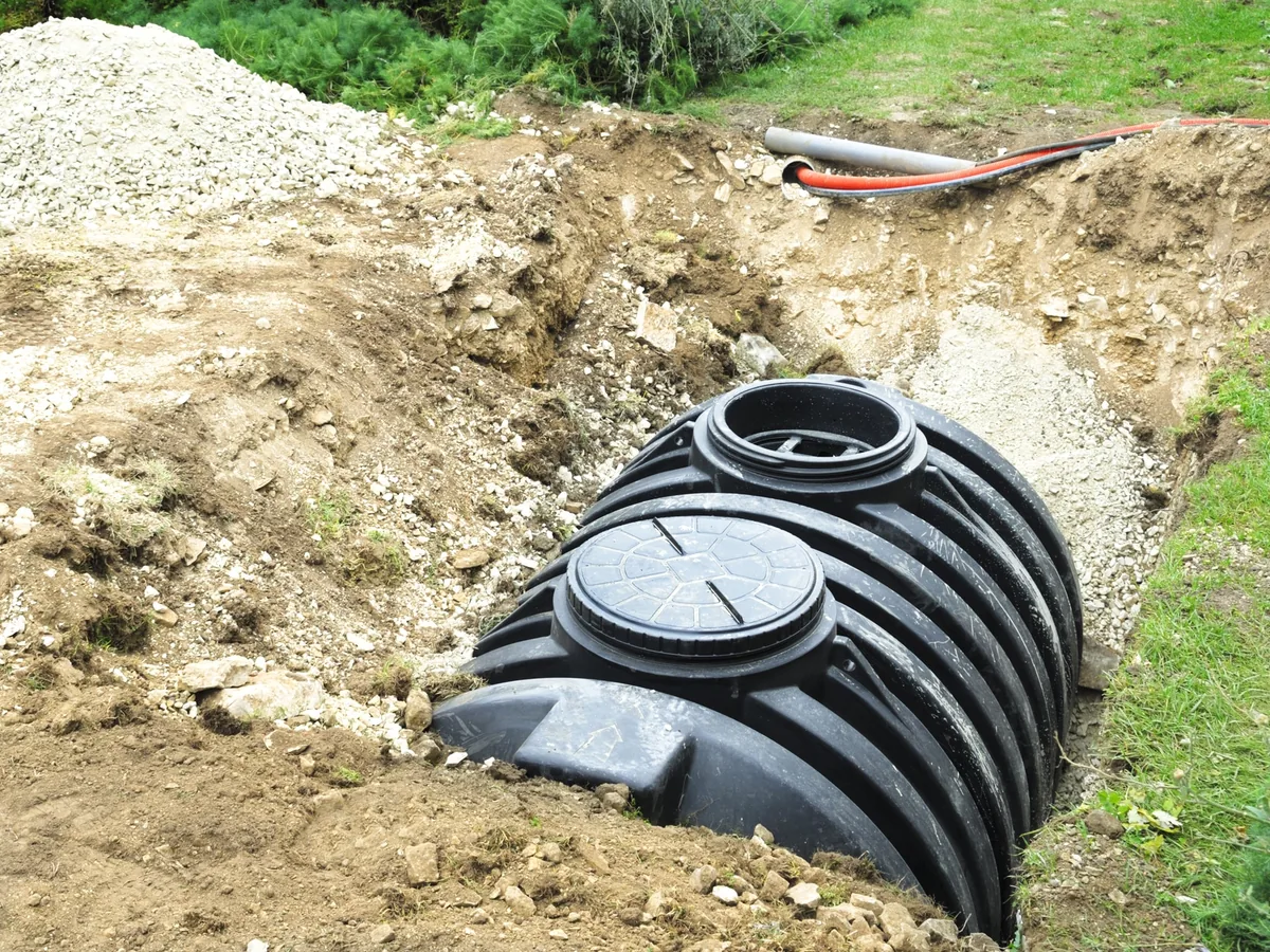 Polyethylene septic tank lowered into a dug pit on a rural lot