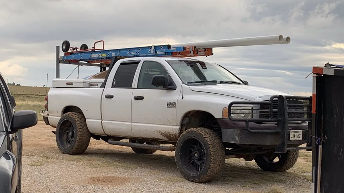 Work truck with pipe racks parked on open high-desert ground in New Mexico