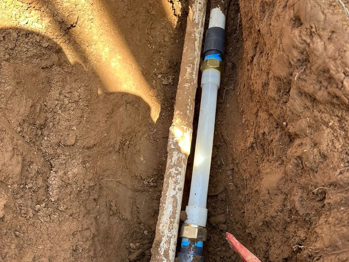 New pipe and coupling joined to an old clay sewer line in an open trench in New Mexico