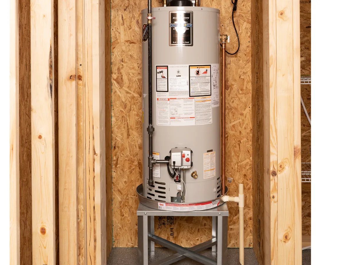 Tank water heater installed on a stand in an unfinished utility space