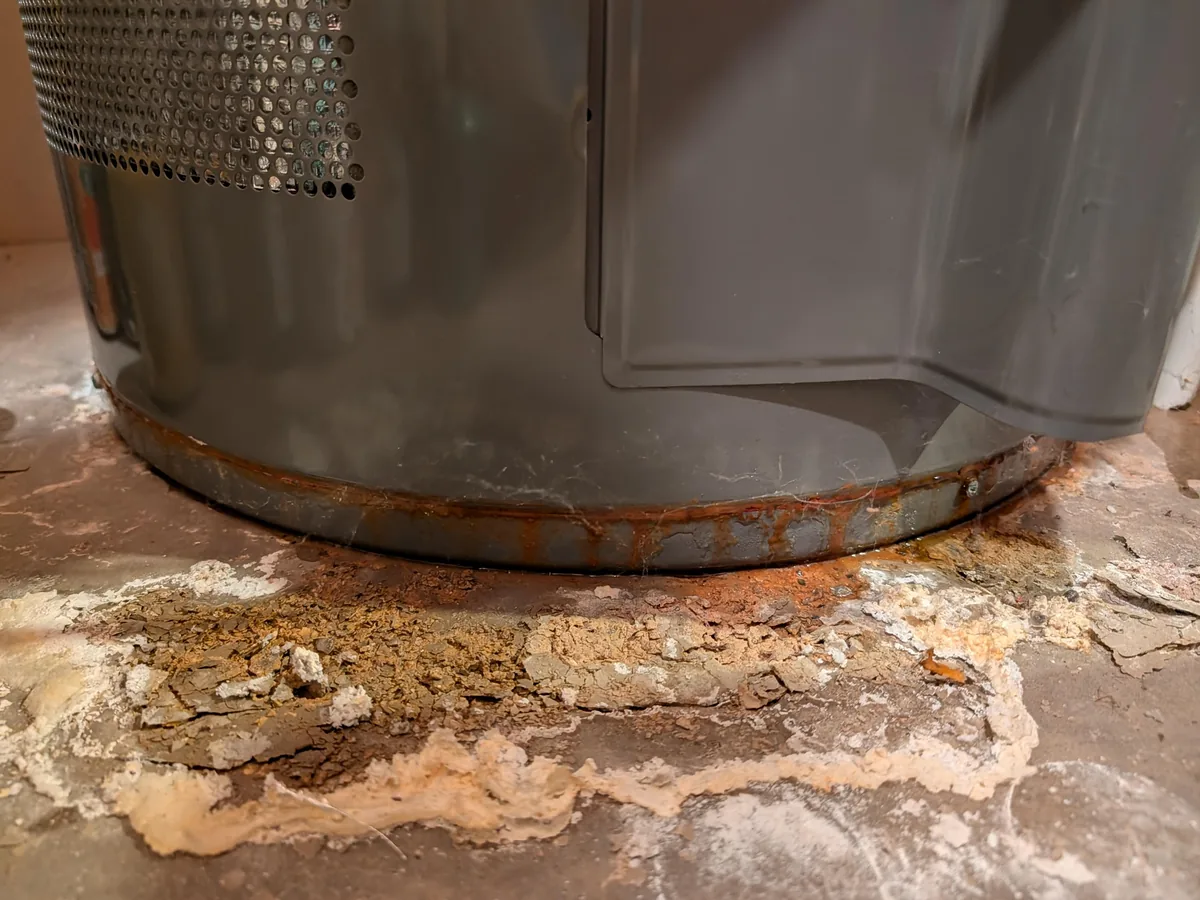 Rust and corrosion spreading around the base of a leaking water heater
